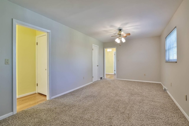 empty room featuring baseboards, ceiling fan, and light colored carpet