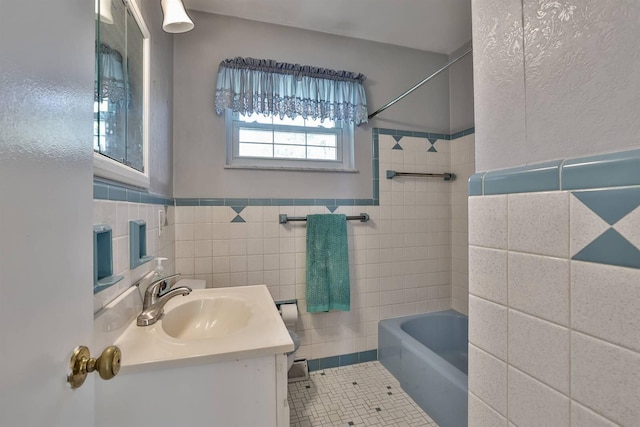 bathroom featuring tile walls, a wainscoted wall, vanity, tile patterned floors, and washtub / shower combination
