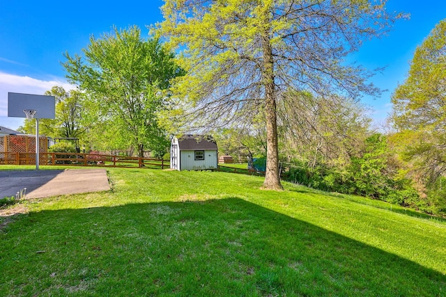 view of yard featuring an outdoor structure, fence, and a storage shed