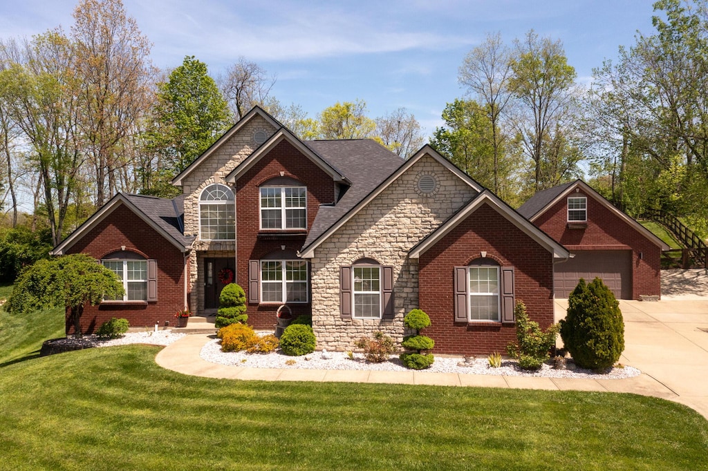 view of front of property featuring brick siding, a front yard, driveway, and stone siding