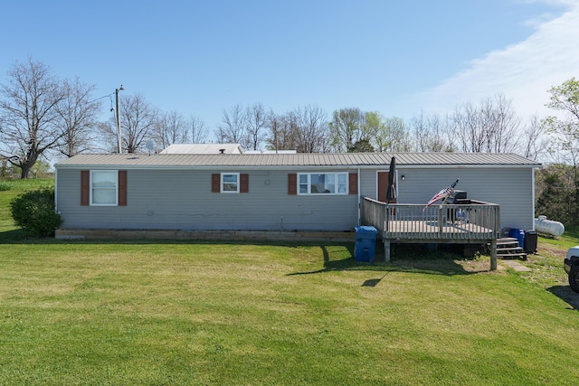 rear view of property with a deck, a yard, and metal roof