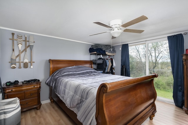 bedroom with wood finished floors, ceiling fan, and ornamental molding