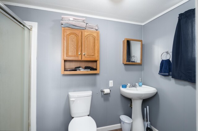 full bathroom with toilet, a shower with door, and a sink