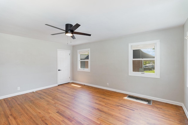 spare room featuring baseboards, ceiling fan, light wood finished floors, and visible vents