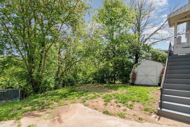 view of yard with an outdoor structure, fence, stairs, and a storage unit