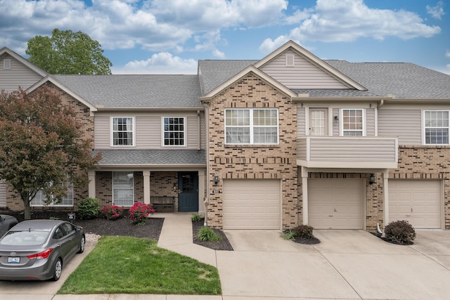 view of property featuring driveway, brick siding, an attached garage, and a shingled roof