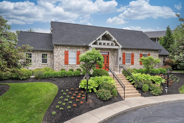 view of front of property featuring stone siding and a shingled roof