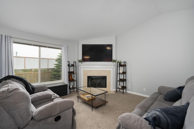 living room featuring lofted ceiling, light carpet, a tiled fireplace, and baseboards