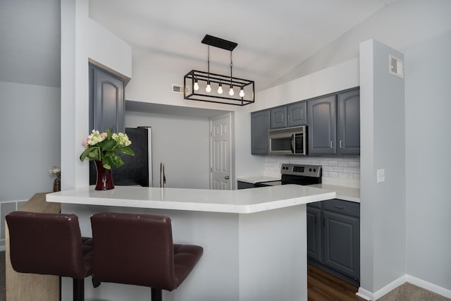 kitchen with stainless steel appliances, gray cabinetry, a peninsula, vaulted ceiling, and backsplash