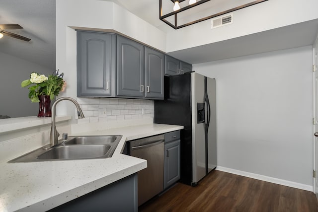 kitchen featuring appliances with stainless steel finishes, a sink, gray cabinets, and dark wood-style floors
