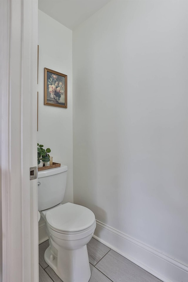 bathroom with toilet, tile patterned flooring, and baseboards