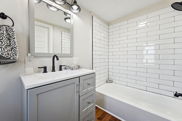 full bath featuring washtub / shower combination, vanity, and wood finished floors