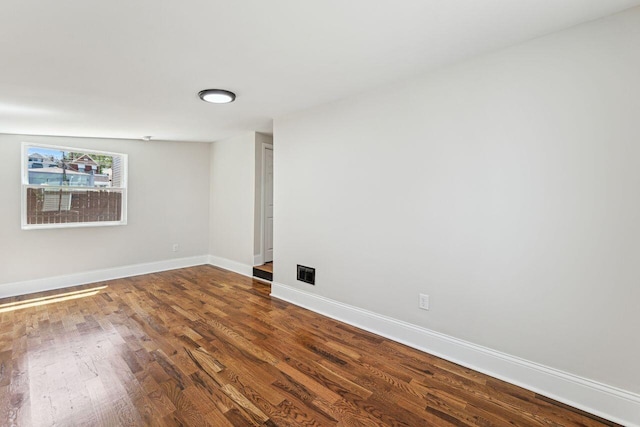 unfurnished room featuring baseboards, dark wood-style floors, and visible vents