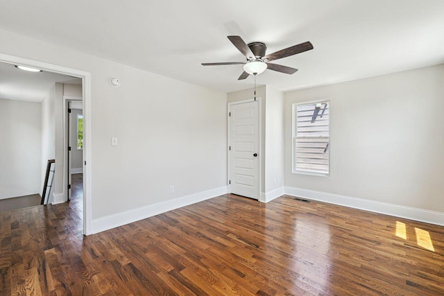unfurnished room with ceiling fan, dark wood-style floors, visible vents, and a wealth of natural light