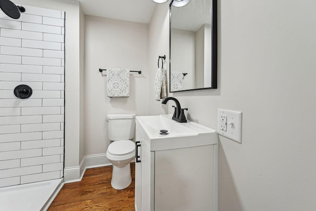 bathroom featuring vanity, toilet, baseboards, a shower stall, and wood finished floors
