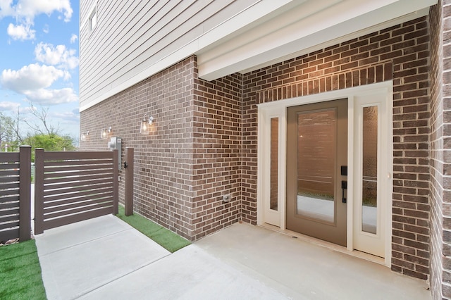 view of exterior entry featuring a gate and brick siding