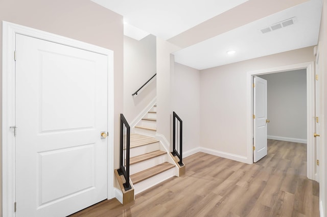 staircase featuring baseboards, visible vents, wood finished floors, and recessed lighting