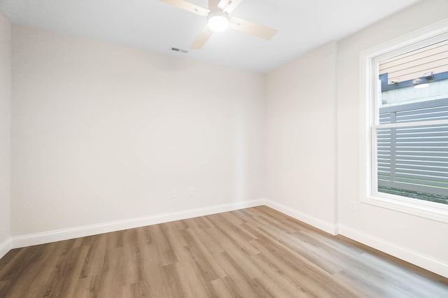 spare room featuring ceiling fan, light wood-type flooring, visible vents, and baseboards