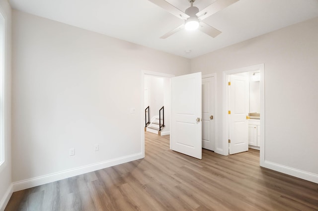 unfurnished bedroom with connected bathroom, wood finished floors, and baseboards