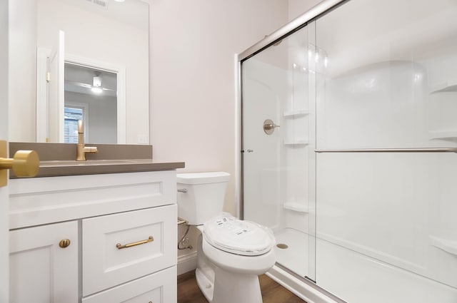 full bath with a shower stall, vanity, toilet, visible vents, and wood finished floors