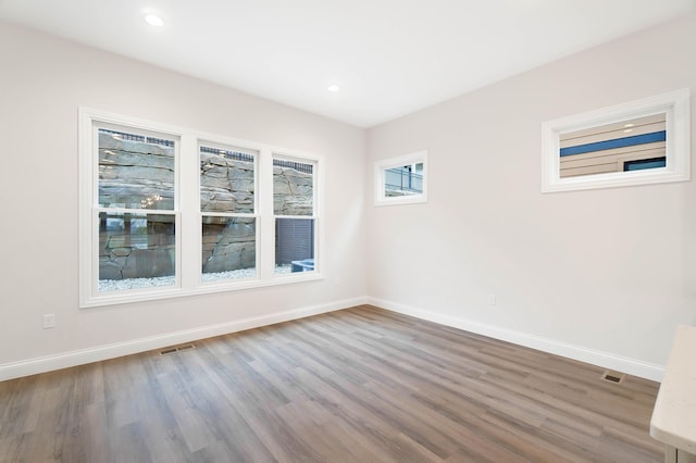 unfurnished room with wood finished floors, visible vents, recessed lighting, and baseboards