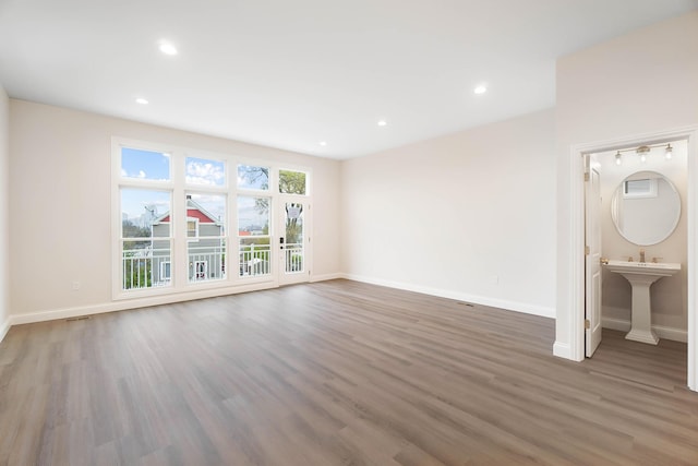 unfurnished living room featuring recessed lighting, wood finished floors, and baseboards