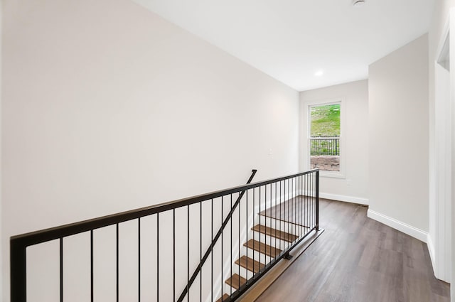 hall with baseboards, wood finished floors, and an upstairs landing