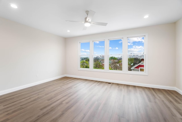 empty room with recessed lighting, wood finished floors, ceiling fan, baseboards, and visible vents