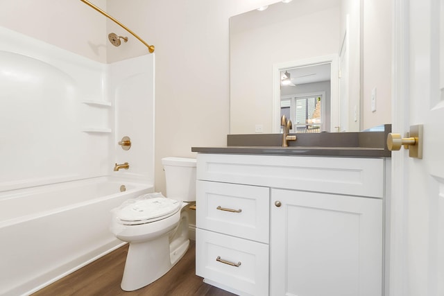 bathroom with wood finished floors, toilet, tub / shower combination, and vanity