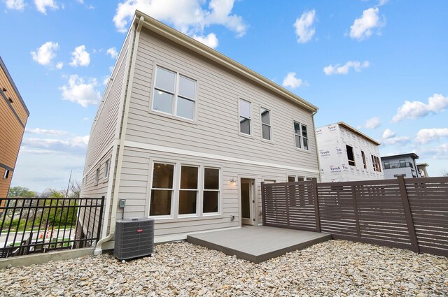 back of house with a fenced backyard and central AC unit