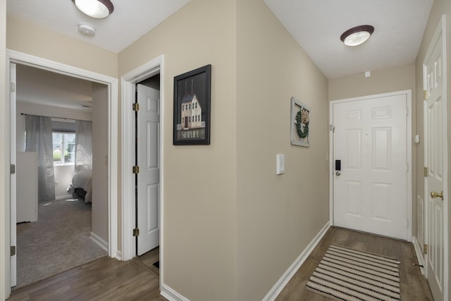 hall featuring dark wood-style flooring and baseboards