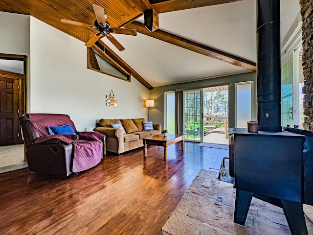 living area featuring a wood stove, wood finished floors, beam ceiling, high vaulted ceiling, and a ceiling fan