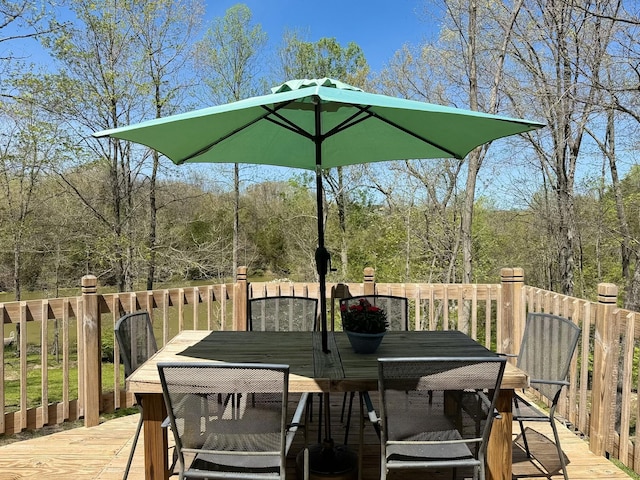 deck with outdoor dining area and a wooded view