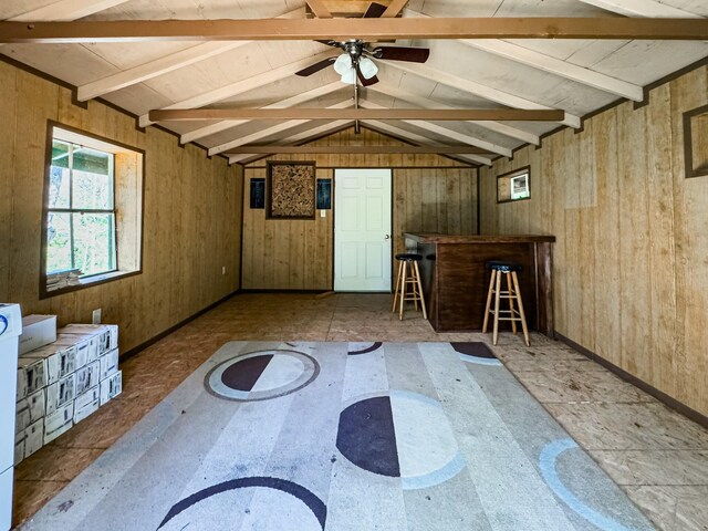 interior space with wooden walls, vaulted ceiling with beams, ceiling fan, and a bar