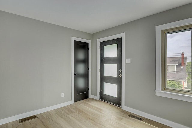 foyer with baseboards, visible vents, and light wood-type flooring
