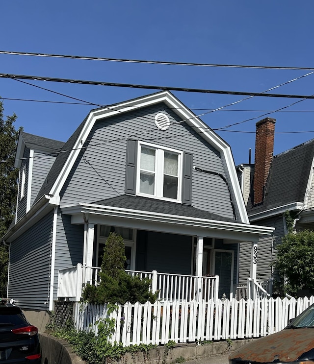 colonial inspired home featuring a porch and a gambrel roof