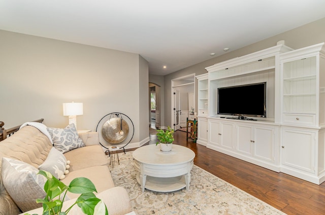 living area featuring baseboards, recessed lighting, arched walkways, and dark wood-type flooring