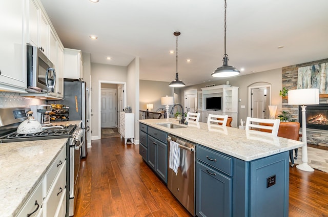 kitchen with a sink, blue cabinetry, white cabinetry, appliances with stainless steel finishes, and open floor plan