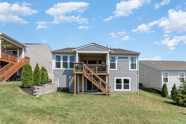 back of property with a deck, stairway, and a yard
