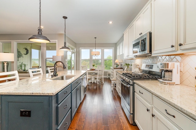 kitchen with tasteful backsplash, gray cabinets, stainless steel appliances, a sink, and dark wood-type flooring