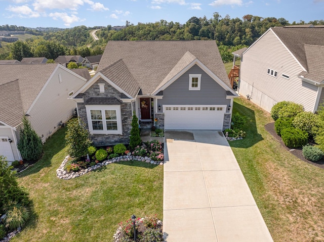 craftsman-style house with a shingled roof, a garage, stone siding, a front lawn, and concrete driveway
