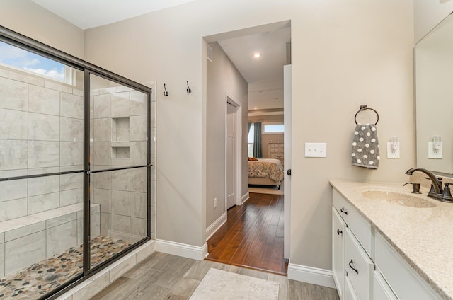 bathroom with connected bathroom, wood finished floors, a shower stall, and baseboards