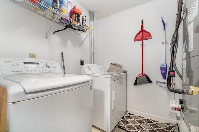washroom featuring laundry area, heating unit, baseboards, and washer and dryer