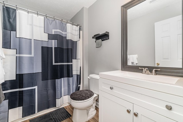 bathroom with vanity, a textured ceiling, wood finished floors, and toilet