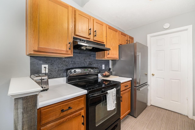 kitchen with freestanding refrigerator, light countertops, under cabinet range hood, black electric range, and tasteful backsplash