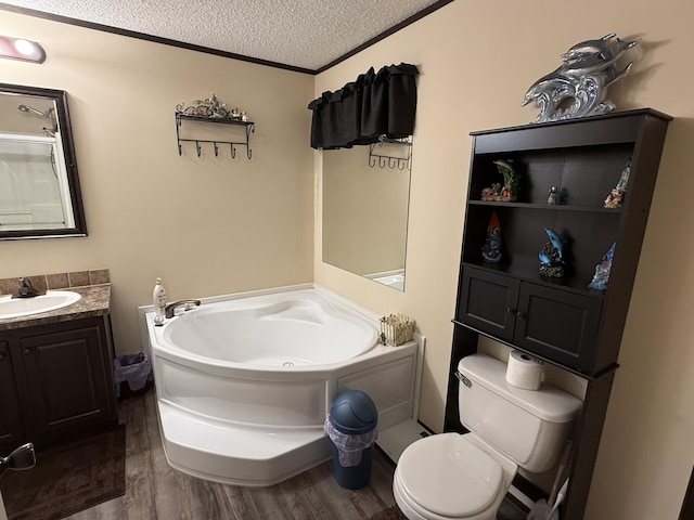 bathroom featuring wood finished floors, a garden tub, toilet, vanity, and a textured ceiling