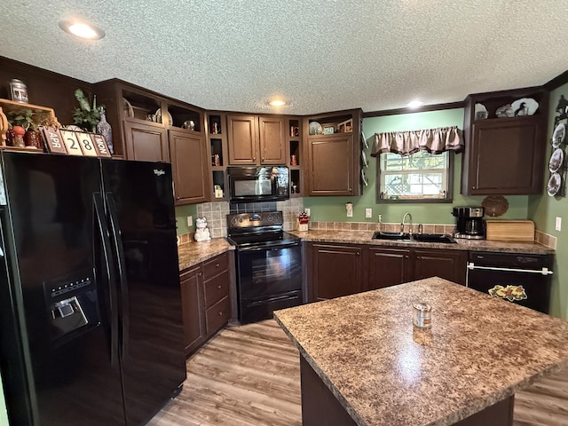 kitchen featuring a textured ceiling, open shelves, a sink, black appliances, and light wood-type flooring