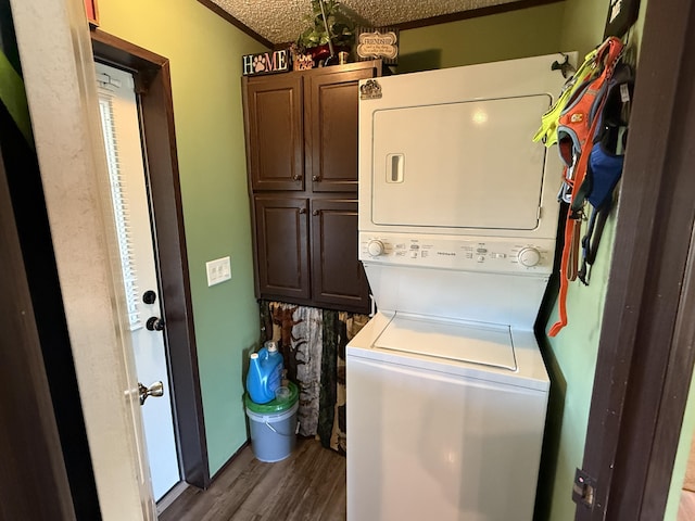washroom with stacked washing maching and dryer, a textured ceiling, wood finished floors, and cabinet space