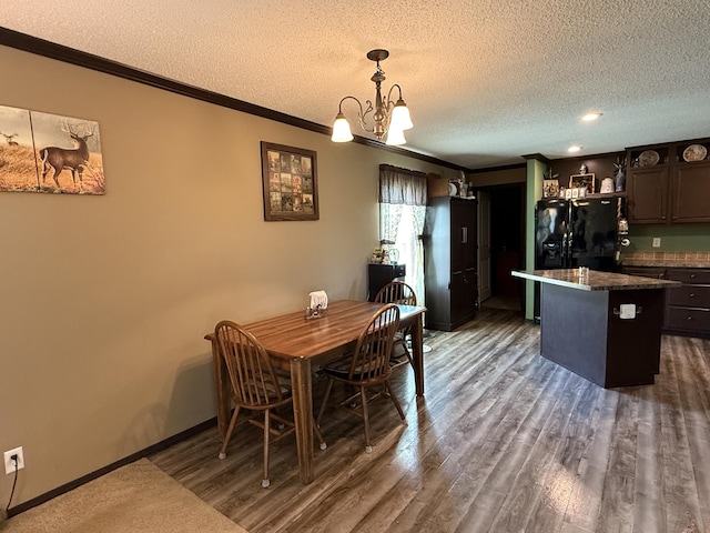 dining space featuring a chandelier, ornamental molding, a textured ceiling, and wood finished floors