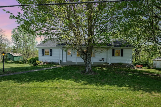 view of front facade featuring a porch, roof with shingles, and a yard